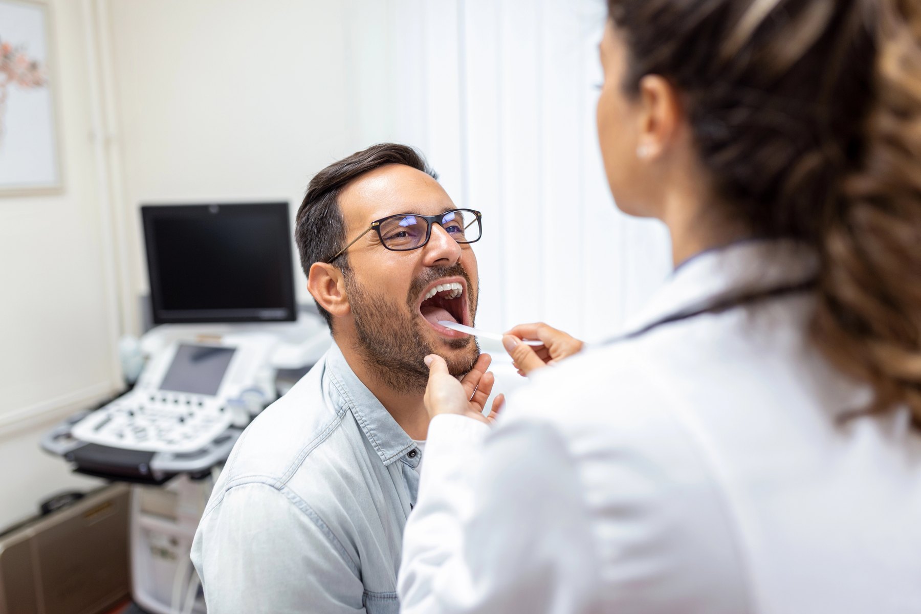 Clinician examining a patient’s mouth with an oral inspection tool