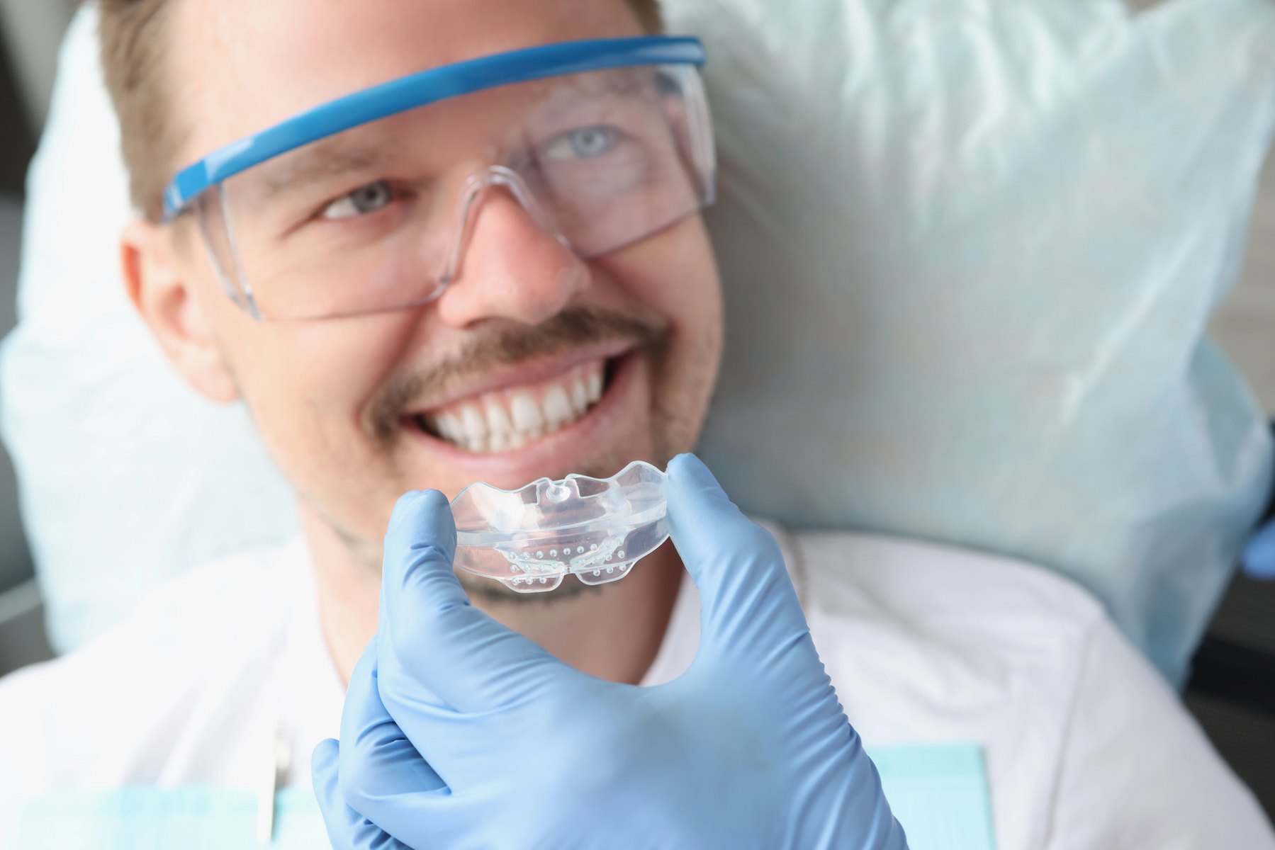 Man holding a clear dental appliance near his smile