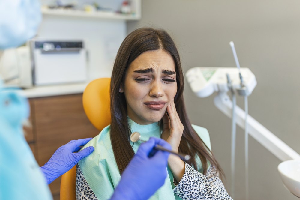 Woman holding her cheek in a dental chair