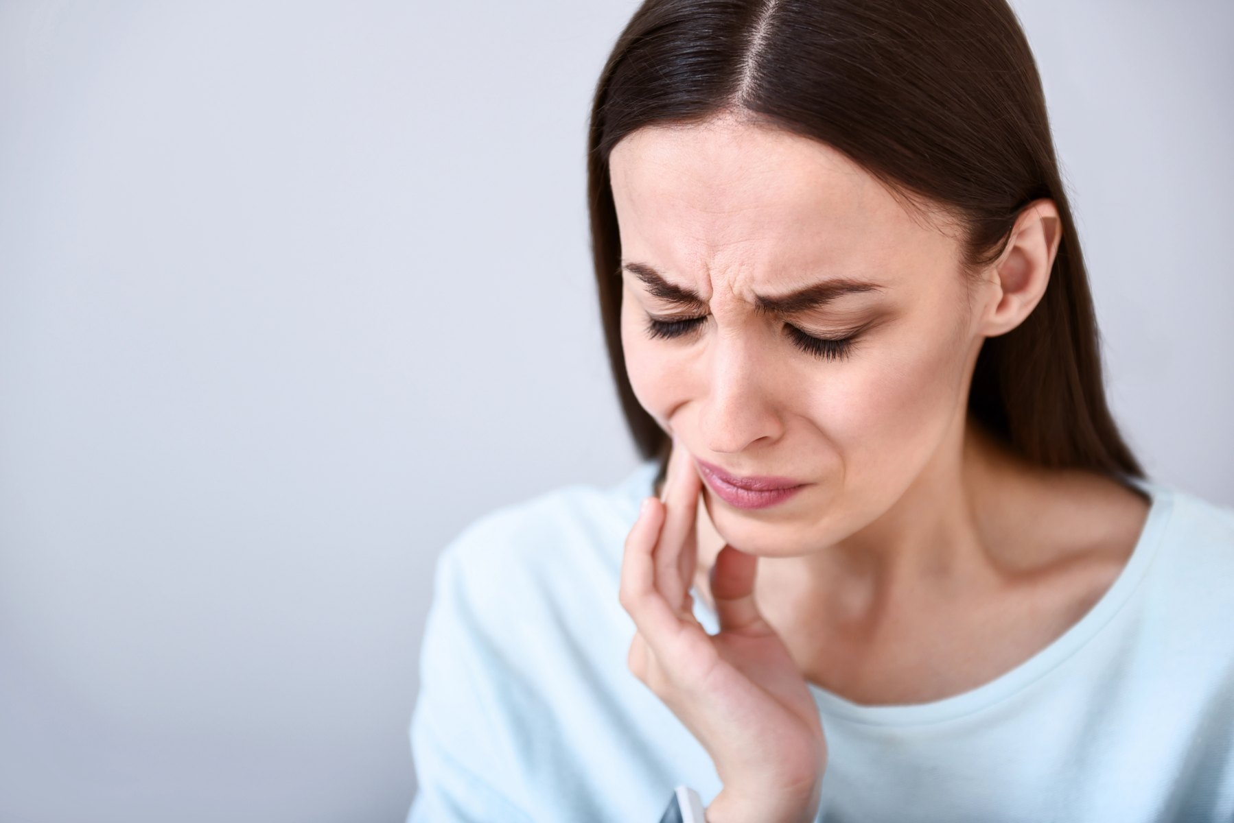 Woman holding her cheek because of tooth pain